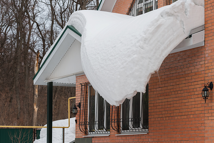 Beaucoup de neige sur le point de tomber du toit d'une maison